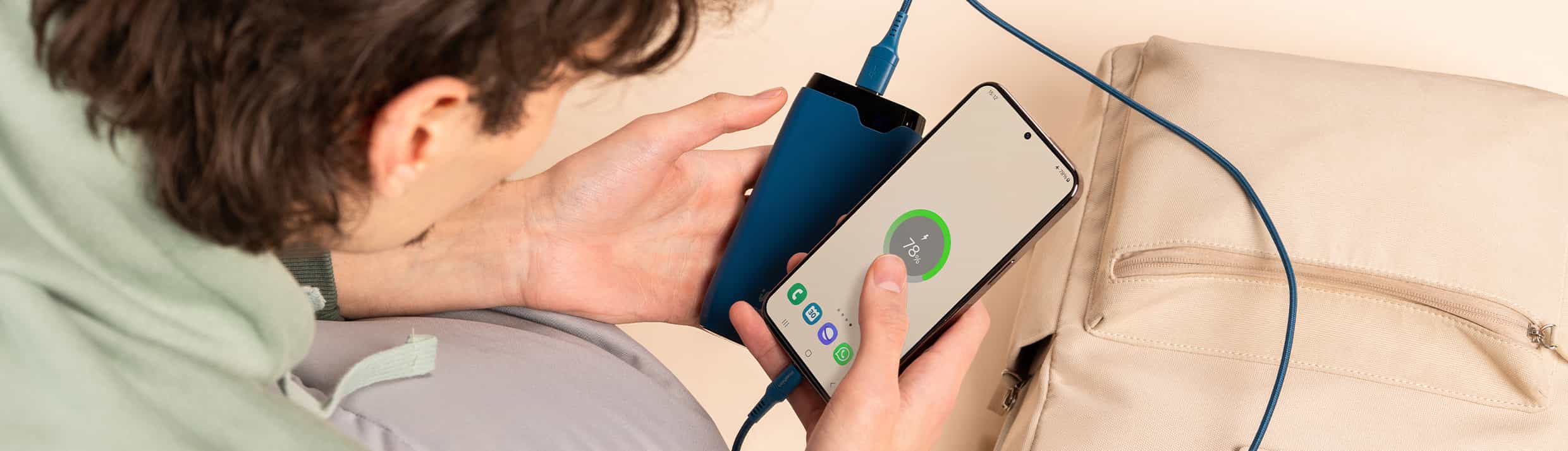 Le téléphone est connecté à une batterie externe et repose sur une valise à l'aéroport.