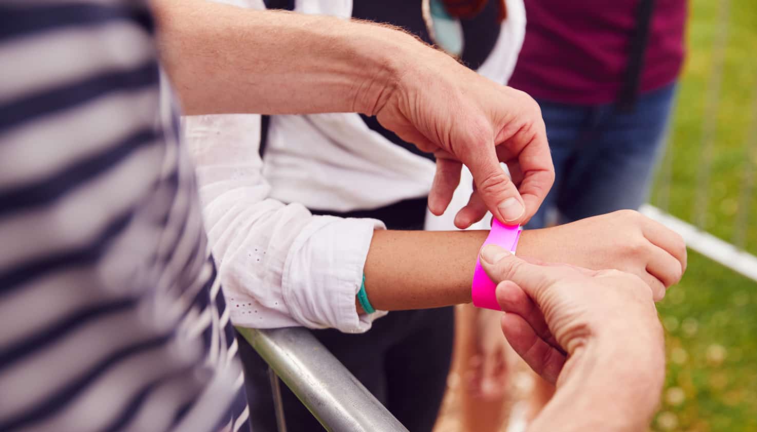 À l'entrée du festival, une personne se voit remettre un bracelet rose, comme preuve d'accès au site du festival.