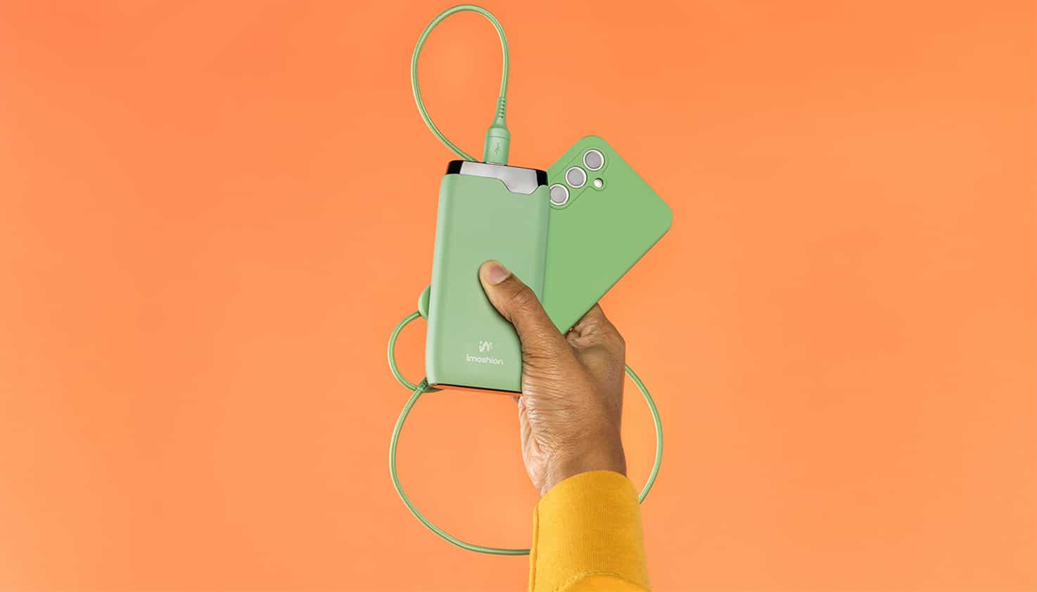 Un fond orange vif avec une batterie externe vert éclatant assortie à un téléphone.