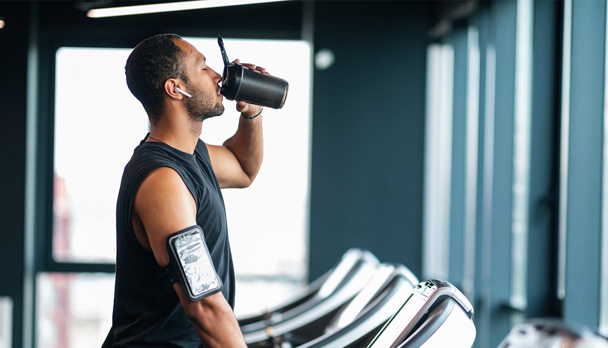 Un homme se tient sur un tapis de course avec des Apple AirPods Pro dans les oreilles en écoutant de la musique.