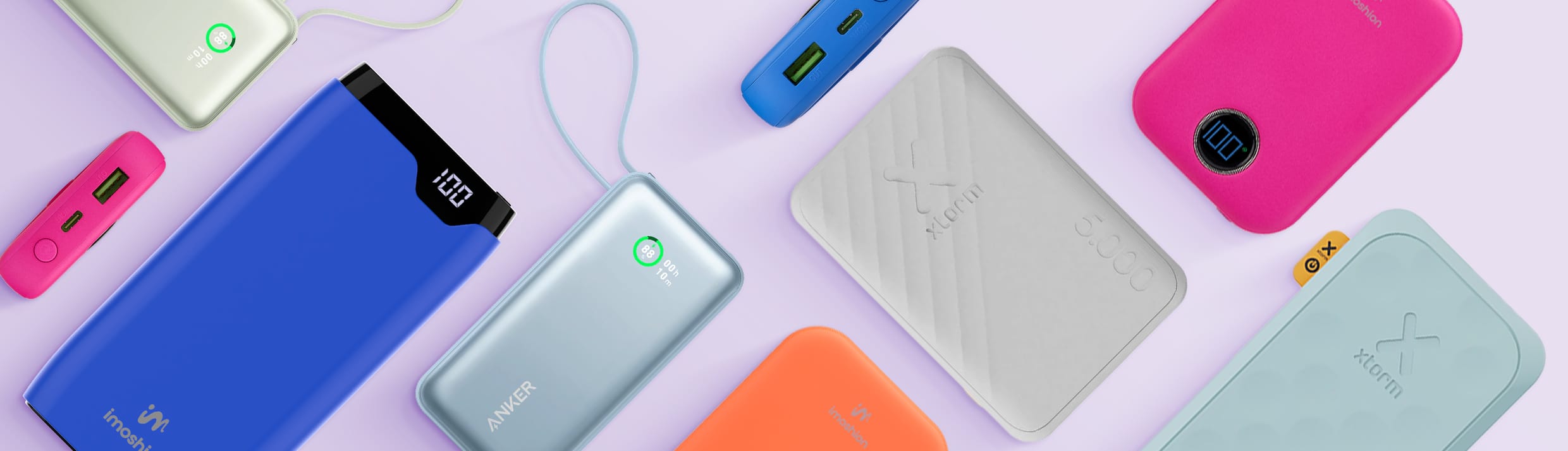 Un aper&ccedil;u des diff&eacute;rentes marques, tailles, couleurs et types de batteries externes, certaines pos&eacute;es &agrave; plat, d&rsquo;autres sur le c&ocirc;t&eacute;. Notamment des batteries externes Anker, Xtorm et imoshion, sur un fond violet clair.