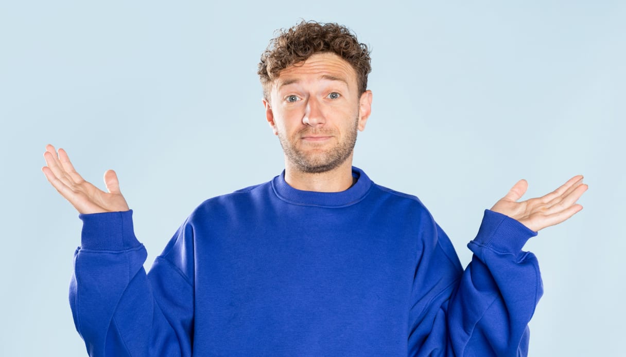 Un homme vêtu d'un pull bleu cobalt lève les mains en signe d'interrogation.