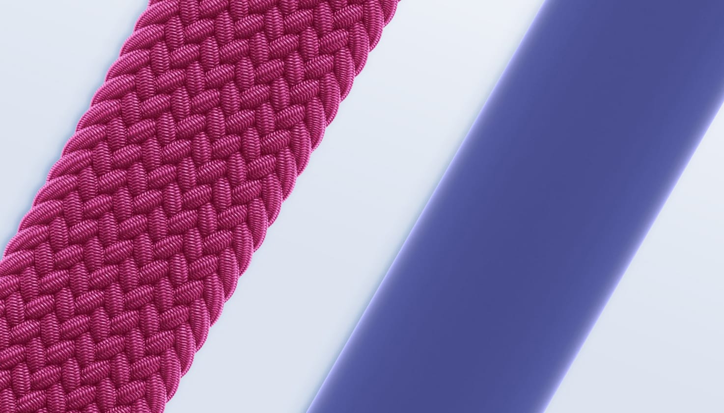 Detailshot van twee Apple solobandjes op een lichtblauwe achtergrond, links een wijnrood gevlochten solobandje en rechts een paars siliconen solobandje.